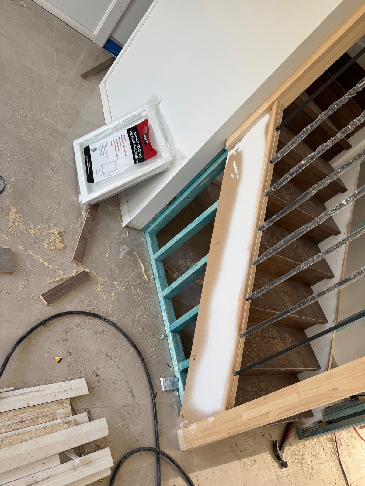 Staircase with timber treads and a timber handrail, wrapped in protective plastic mid fit-out