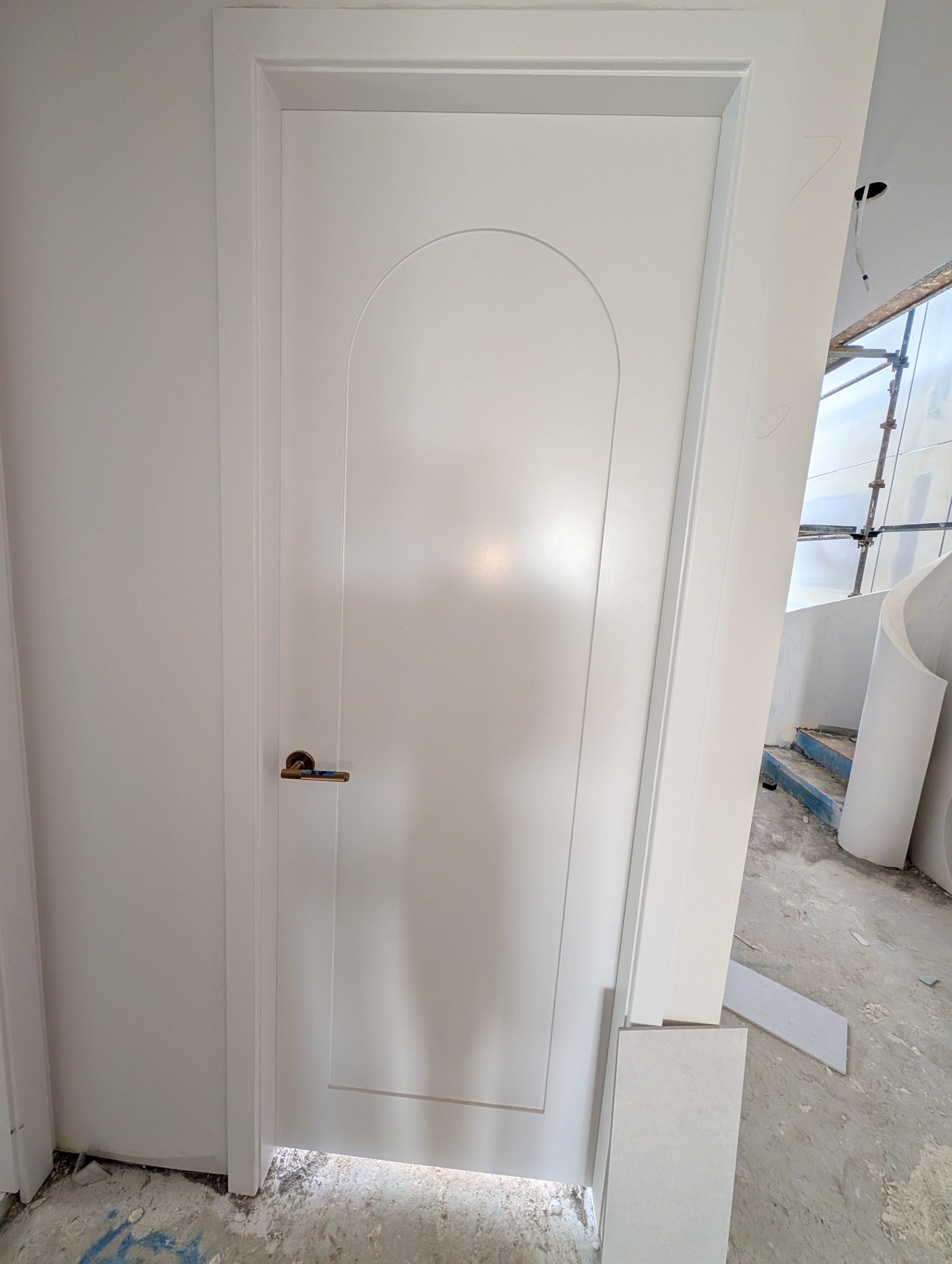 White internal door with a routed arch panel and brass lever handle