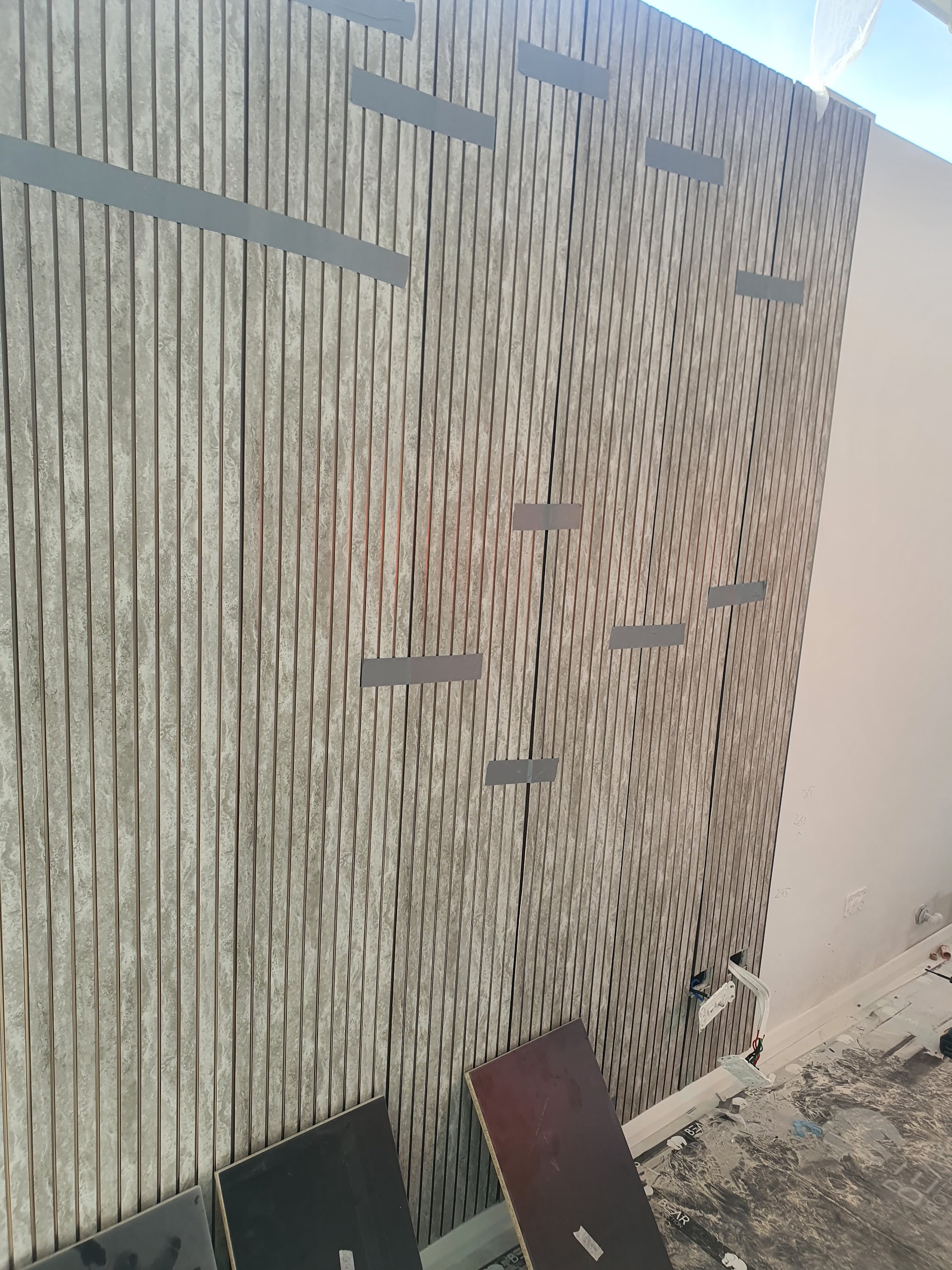 Vertical fluted wall panels being fixed to a feature wall, joints taped