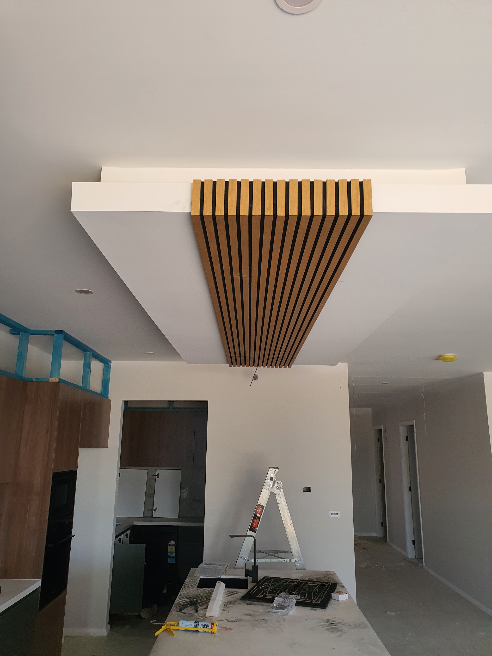 Timber-look slat bulkhead running across the ceiling above a kitchen island